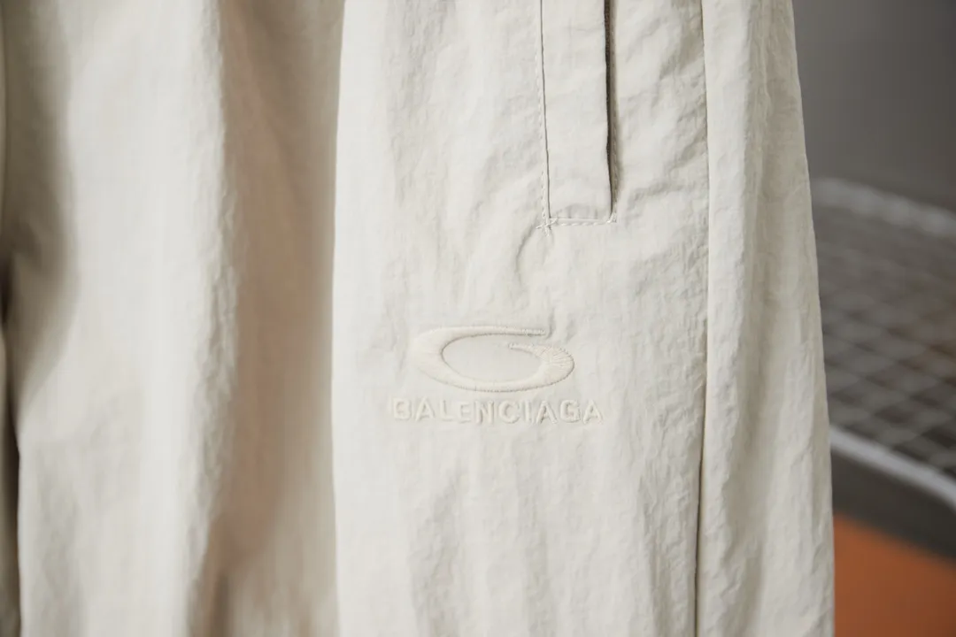 Balenciaga 𝘽𝘼𝙇𝙀𝙉𝘾𝙄𝘼𝙂𝘼 BLCG 26SS 71 front and rear half-circle letter embroidered sports suit Light luxury essential item for daily commuting for men and women Correct version Welcome to compare Detailed features · Customized matt Taslan jacket fabric · The fabric has undergone a waterproof coating process · The interior is made of three-grade polyester bird's eye mesh · OS ultra-loose silhouette design · Side zipper pockets Small stand-up collar design · Internal zipper pocket design · Elastic waistband design at the hem · Customized molded hardware zippers Jacket double puller design · Tajima high-speed embroidery machine with 100,000-needle three-dimensional design · Double side pockets on trousers · Original main mark washed tag brand packaging Color: Black/Milk Apricot Size: 46/48/50/52